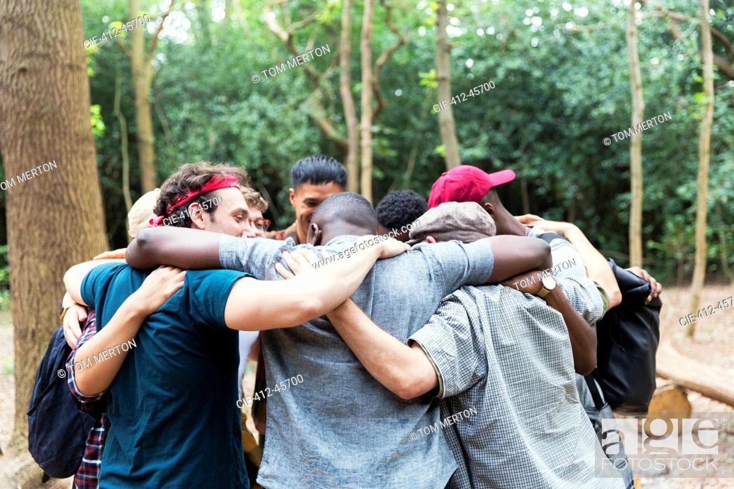 Stock Photo: Men friends hugging in huddle on hike in woods.