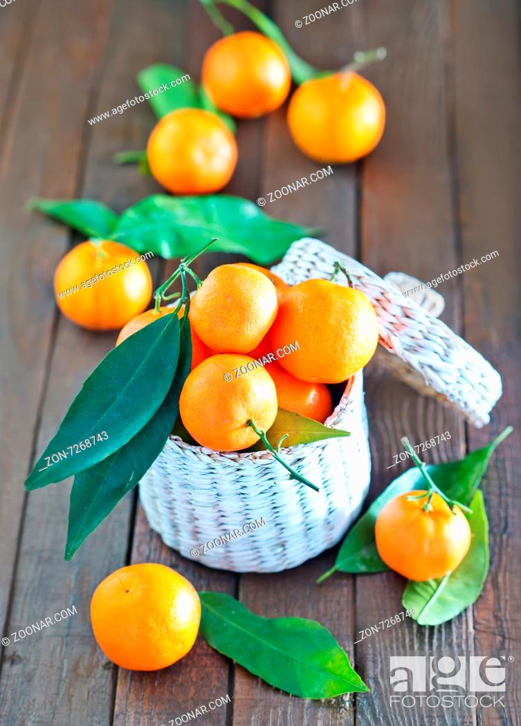 Imagen: fresh tangerines in the white basket and on a table.