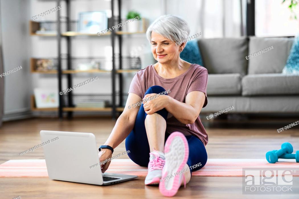 Stock Photo: happy woman with laptop exercising at home.