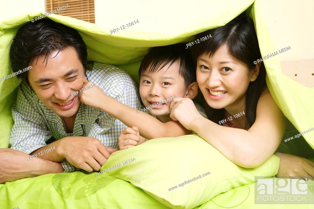 Stock Photo: Family members in quilt with smile.