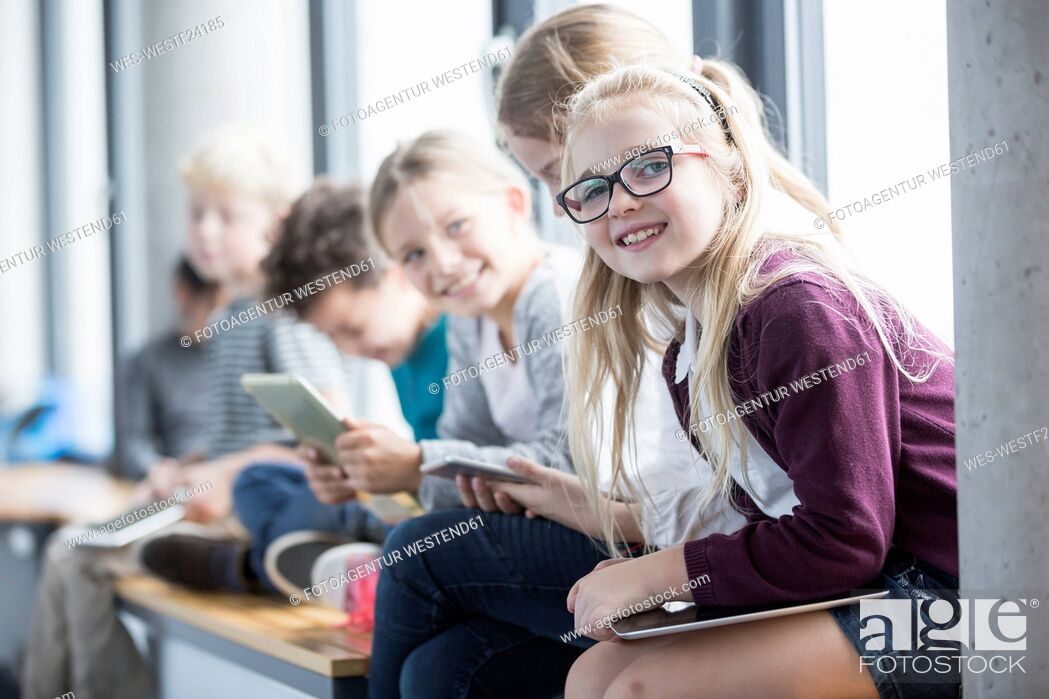 Stock Photo: Smiling pupils with tablets on school corridor.