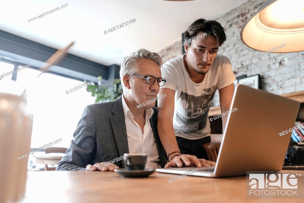 Stock Photo: Father and son working together in cafe, using laptop.