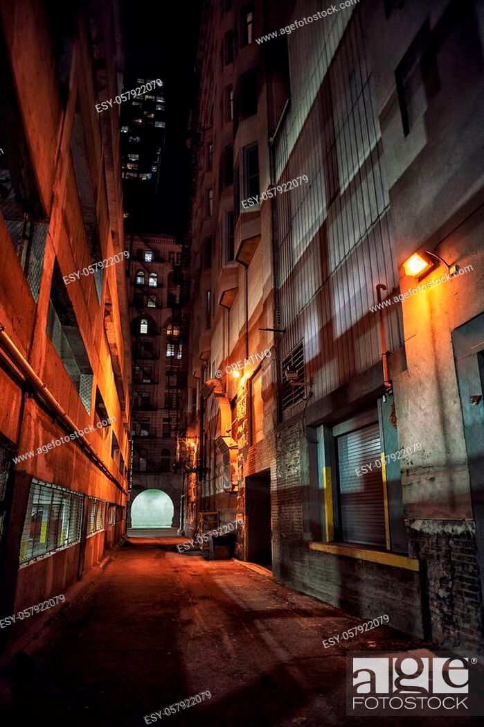 Stock Photo: Dark and eerie downtown urban city alley with a loading dock next to a parking garage at night.