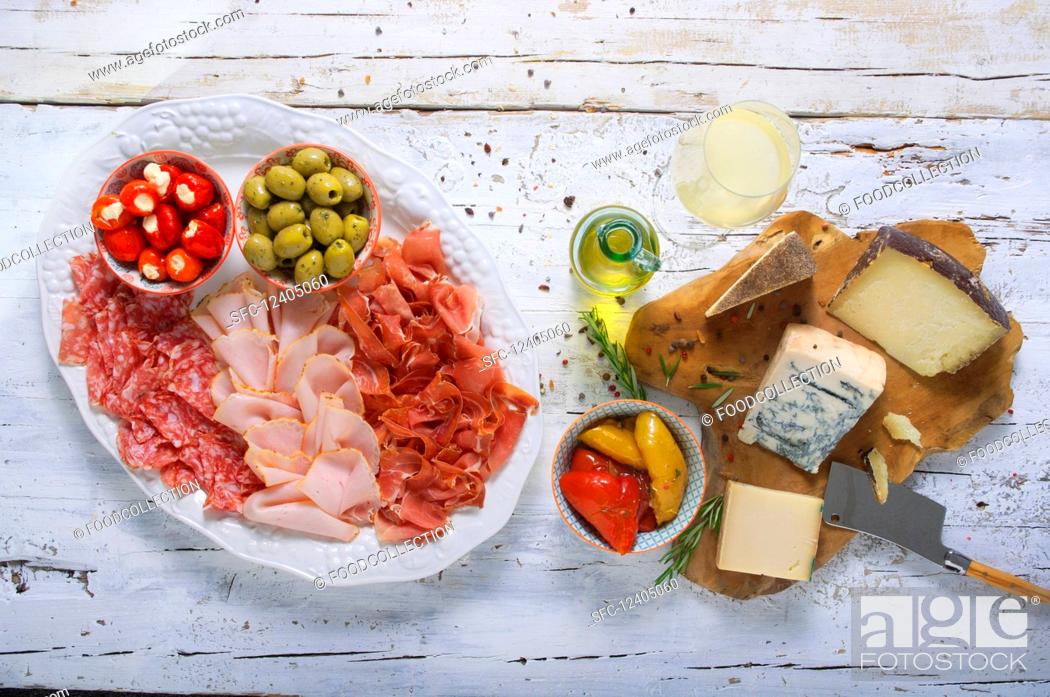 Stock Photo: Cheese and sausage platter with olives, stuffed vegetables and white wine.