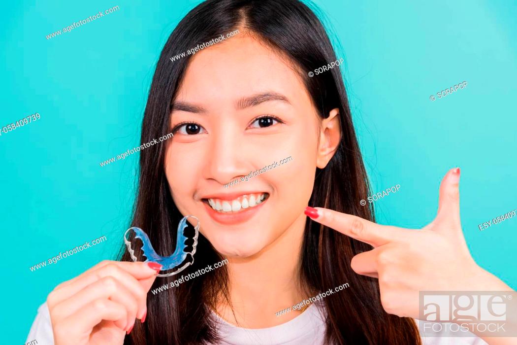 Stock Photo: Female hold teeth retaining tools after removable braces, Portrait young Asian beautiful woman smiling pointing with finger silicone orthodontic retainers for.