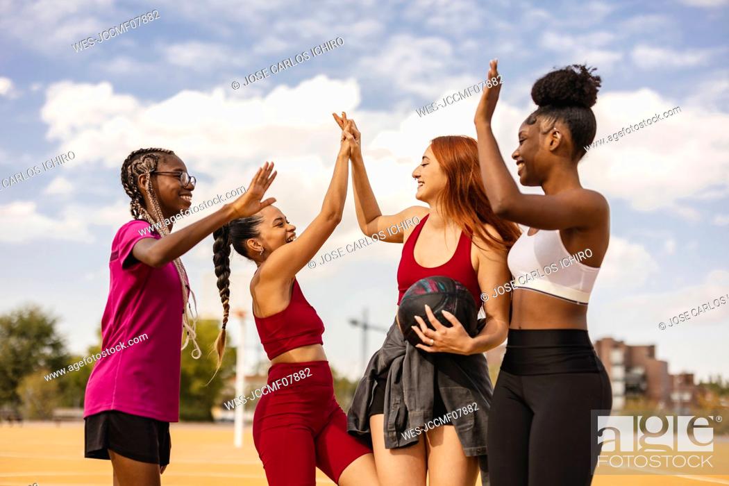Stock Photo: Happy multiracial friends doing high five in sports court.