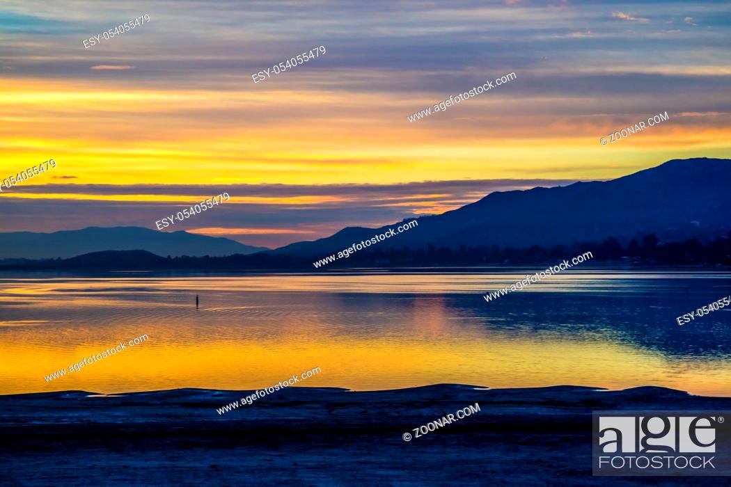 Stock Photo: Romantic sunset in a lake with orange and blue cloudy sky.