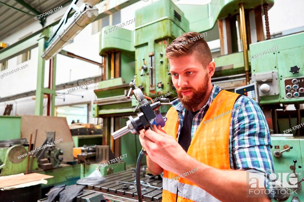 Stock Photo: Arbeiter in der Werkstatt der Metallfabrik prüft konzentriert ein Zentriergerät mit Messuhr.