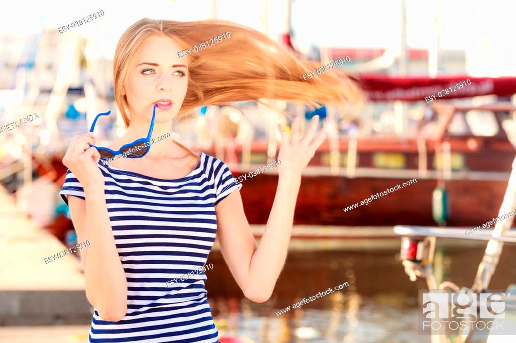 Imagen: Travel tourism and people concept. Fashion blonde girl with blue heart shaped sunglasses in marina against yachts in port.