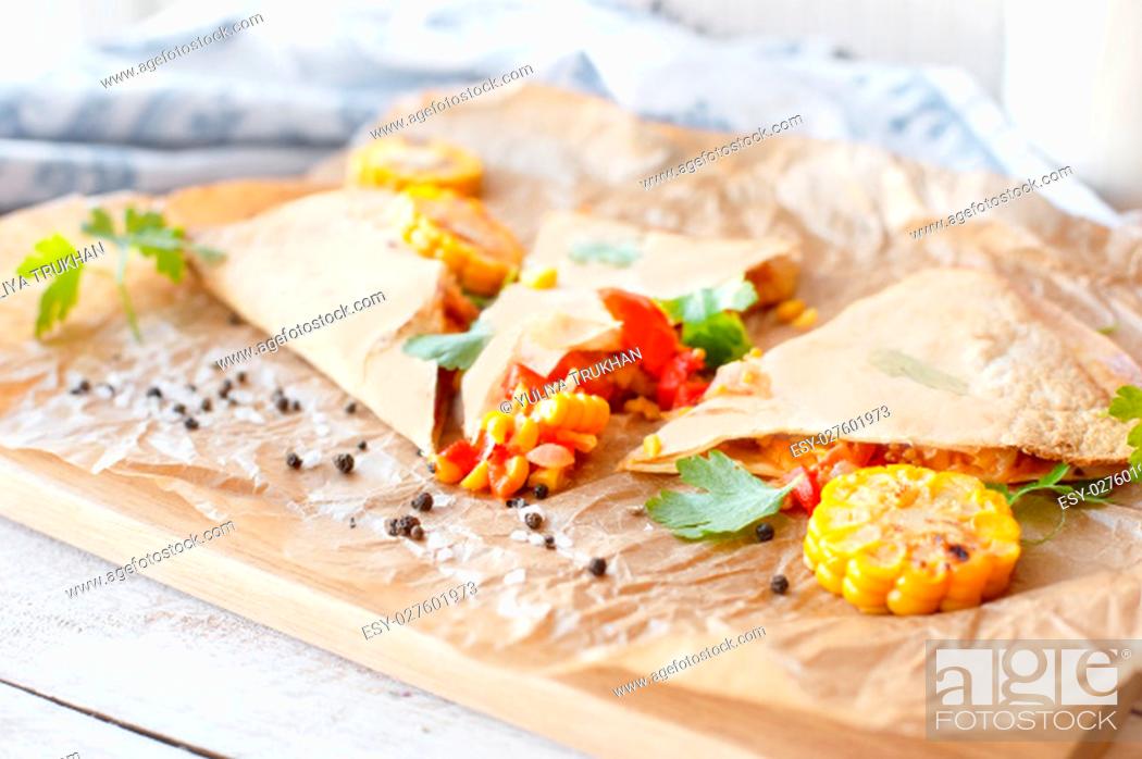 Stock Photo: Mexican Quesadilla wrap with vegetables, corn, sweet pepper and sauces on the parchment and table. horizontal view.