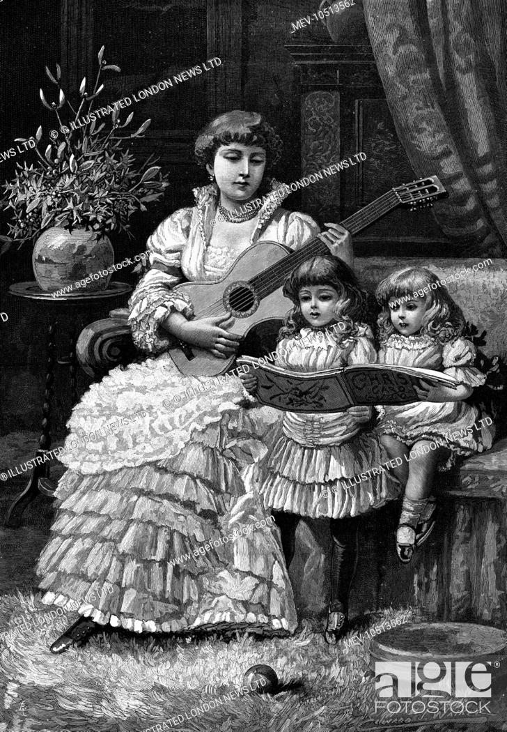 Stock Photo: A woman seated on a couch plays the guitar whilst two little girls sing Christmas carols from a music book. Some holly and mistletoe in a vase complete the.