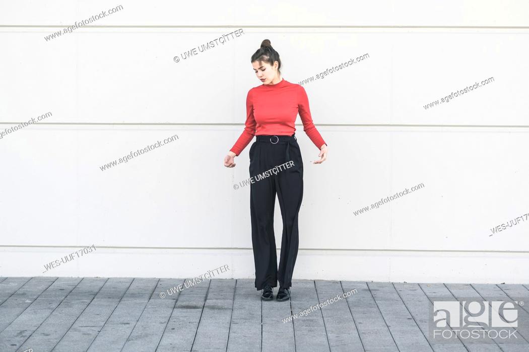 Imagen: Elegant young woman standing at a wall.