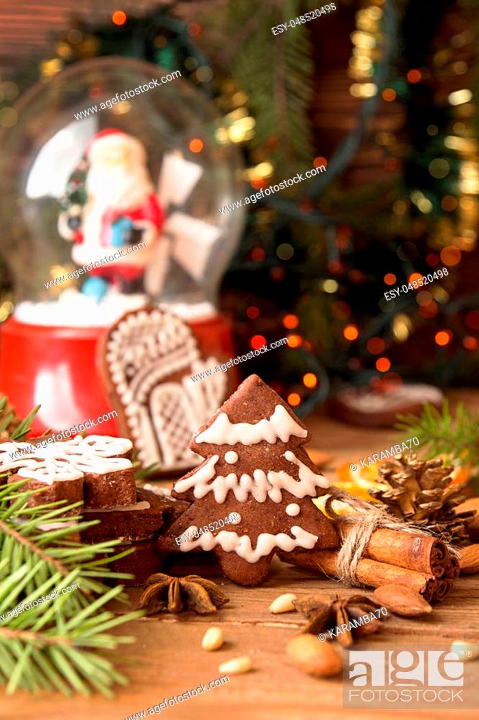 Stock Photo: Christmas gingerbread cookies against background glass sphere with snow and Santa Klaus, branch of fir tree and sparks of Christmas garland.