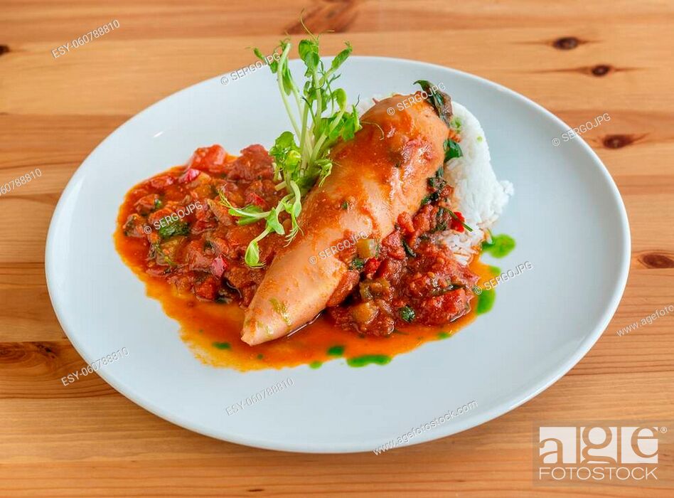 Stock Photo: Stuffed squid with tomato sauce, containing onion and peppers, on top of some cooked rice. High quality photo.