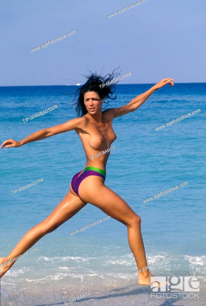 Woman running on the beach in topless.