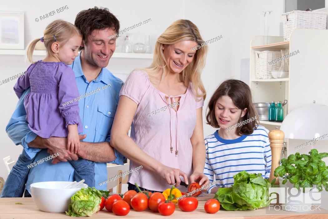 Stock Photo: Germany, Bavaria, Munich, Mother preparing salad with son, father and daughter standing besides them.