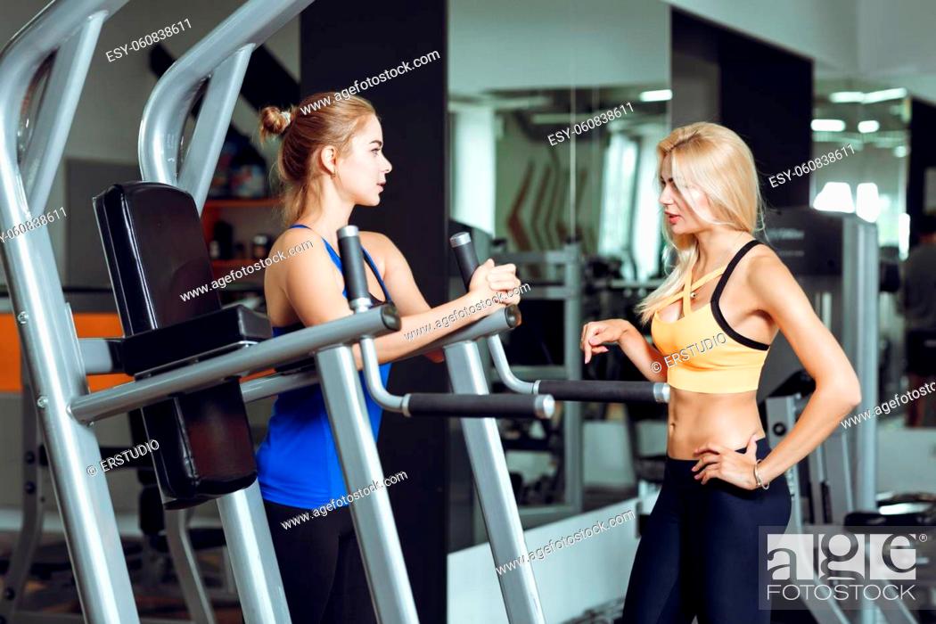 Stock Photo: Two athletic blond women talking in the gym. Girl communicates with the trainer.