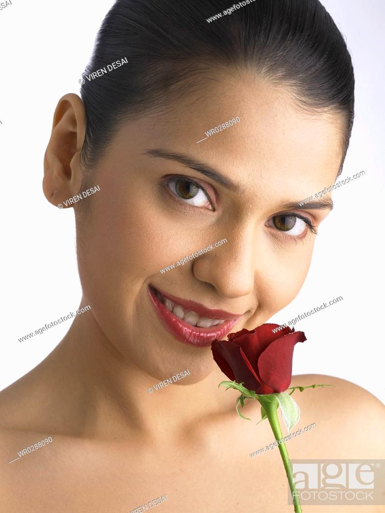 Stock Photo: South Asian Indian woman smiling holding and smelling red rose MR 702.