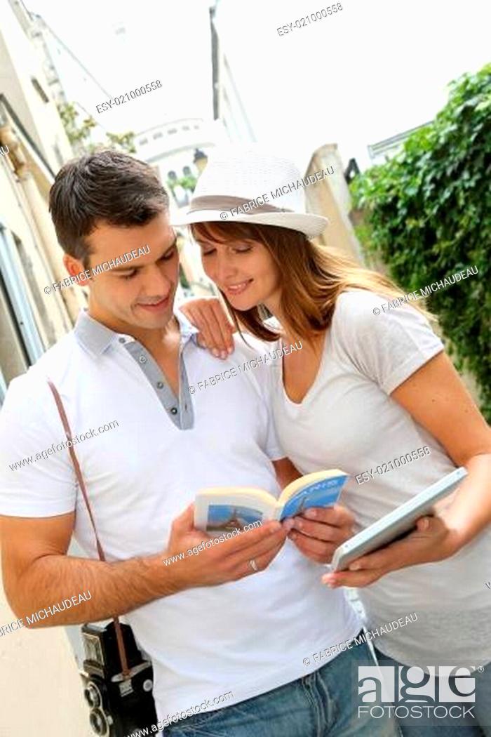 Stock Photo: Couple of tourists using guide and tablet in town.
