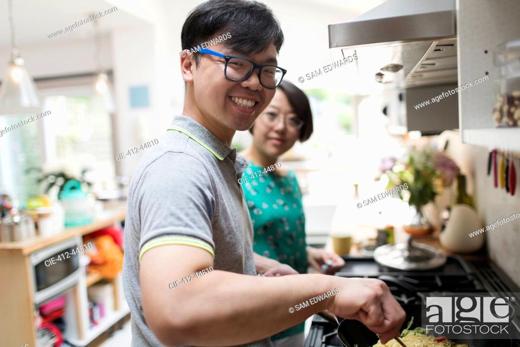 Stock Photo: Portrait smiling couple cooking at stove in kitchen.