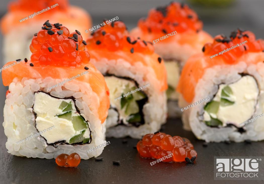 Stock Photo: Philadelphia sushi with red caviar on a black slate board, close up.
