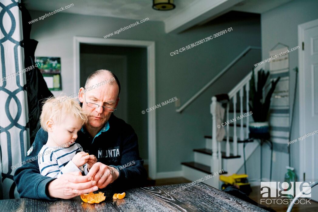 Stock Photo: Grandfather and his grandson eating a mandarin orange together.