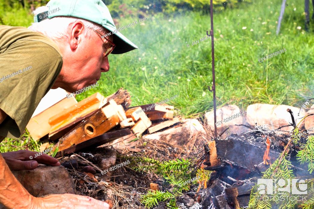 Stock Photo: Senior man making bonfire.