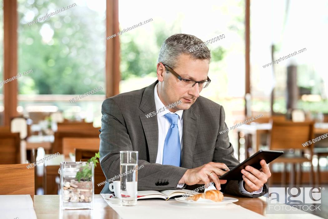 Stock Photo: Businessman in restaurant with digital tablet.