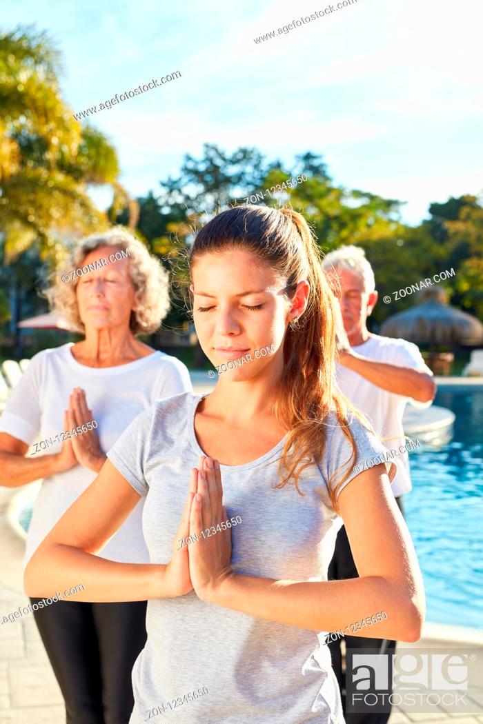 Stock Photo: Junge Frau als Yogalehrer macht eine Übung mit Senioren am Wellness Pool.