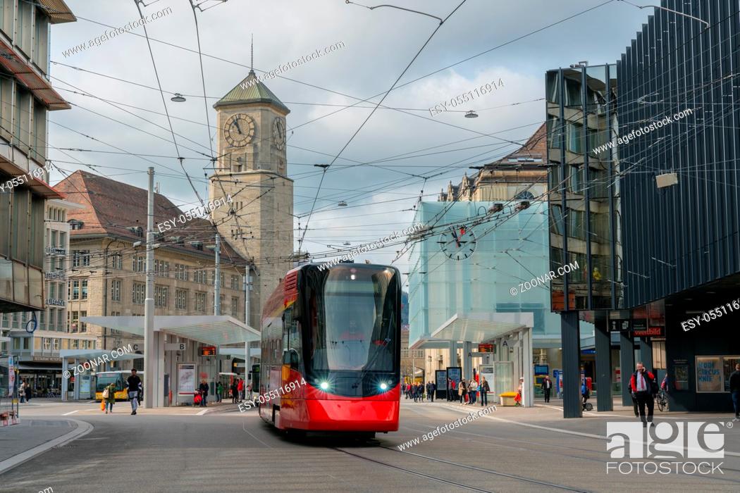Stock Photo: St. Gallen, SG / Switzerland - April 8, 2019: Sankt Gallen train station and local buses and commuter trains leaving the public transport hub with many people.