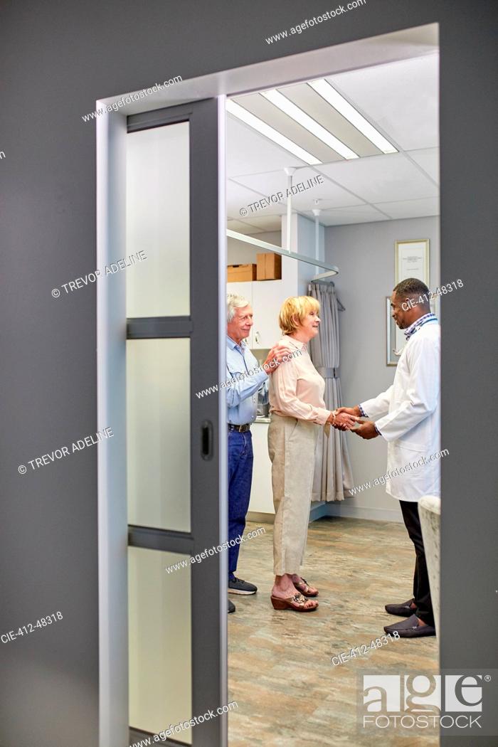 Stock Photo: Doctor shaking hands with senior couple in clinic examination room.