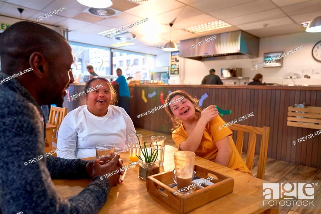 Imagen: Happy young women friends with Down Syndrome laughing in cafe.