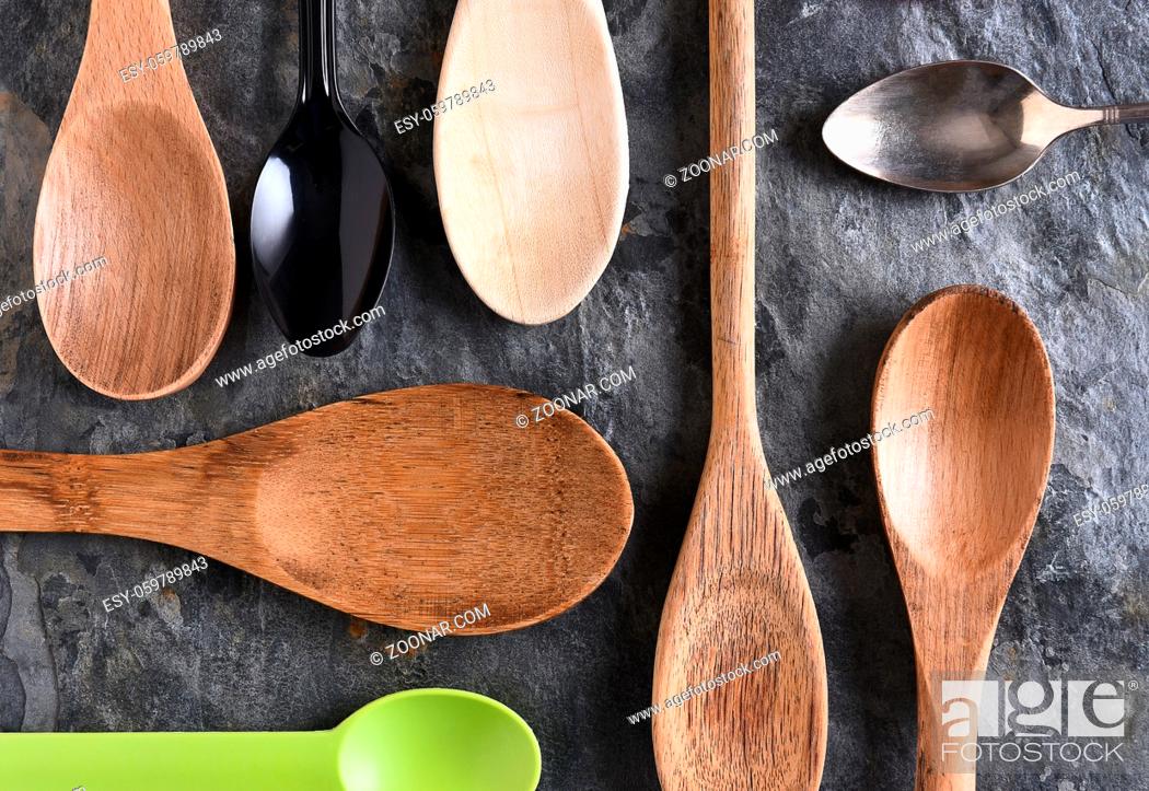 Stock Photo: An assortment of wood, plastic, and metal spoons on a slate surface. Top view in horizontal format.