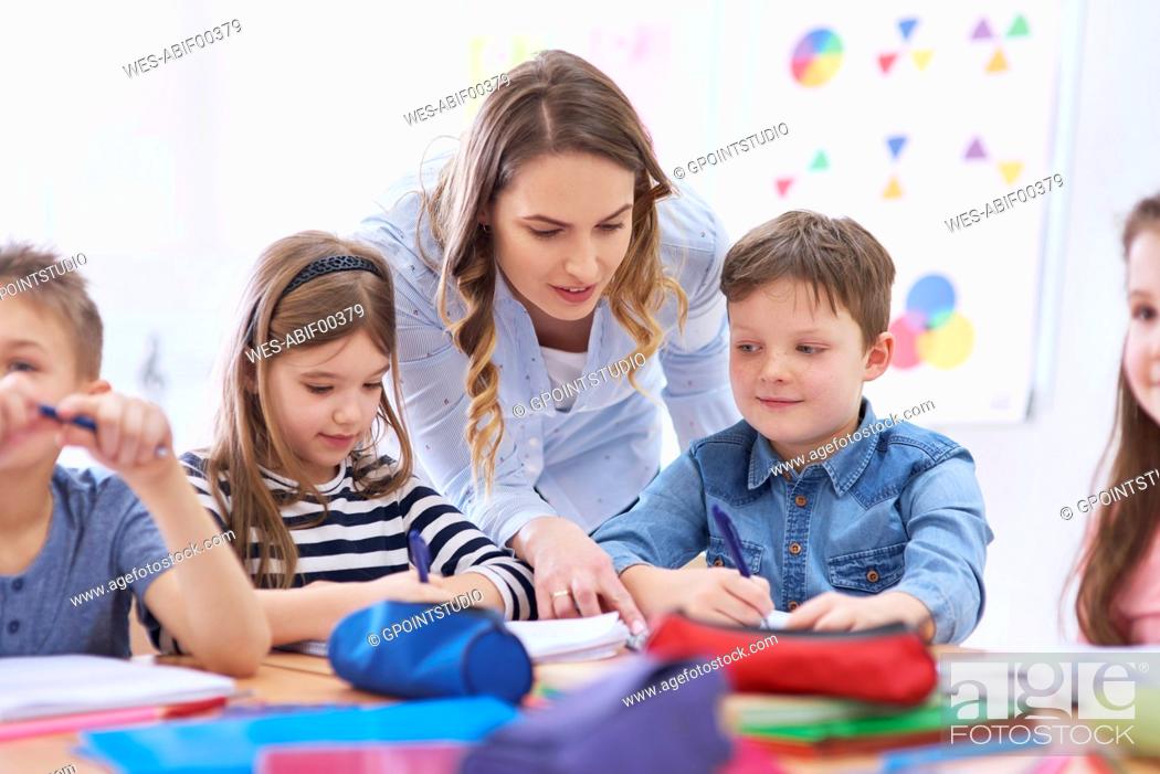 Stock Photo: Teacher helping pupils with their tasks in class.
