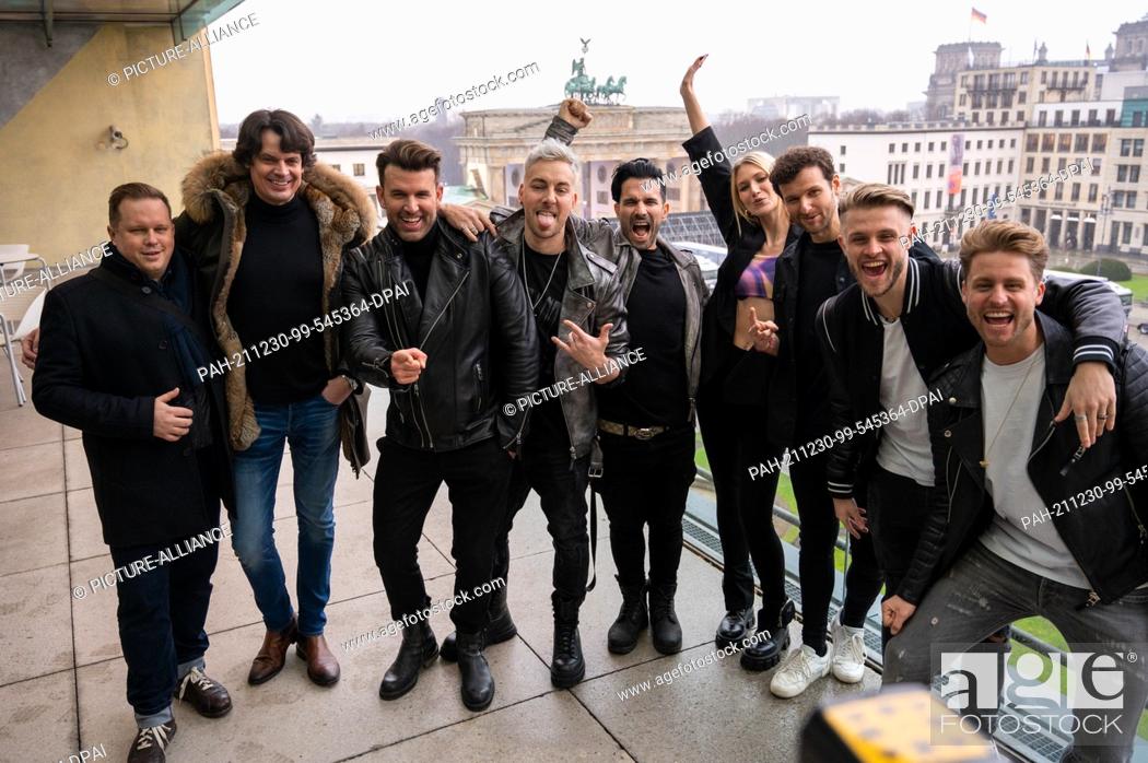 Stock Photo: 30 December 2021, Berlin: The band ""Team 5ünf"" and the band ""Glasperlenspiel"" stand on the terrace of the Academy of Arts in front of the Brandenburg Gate.