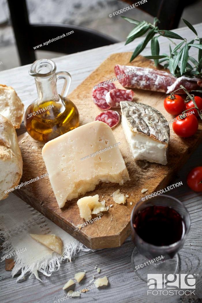 Stock Photo: A rustic starter of sheep's cheese, bread, salami and red wine.