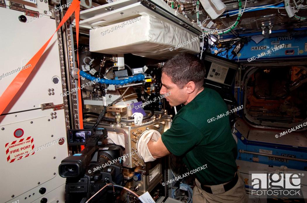 Stock Photo: In the International Space Station's Destiny laboratory, NASA astronaut Mike Hopkins, Expedition 38 flight engineer, sets up the Advanced Colloids Experiment.