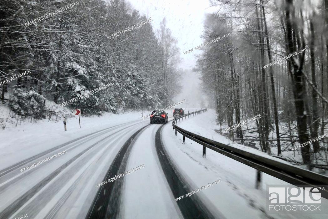 Stock Photo: 19 March 2021, Saxony, Rodewisch: Cars drive along a country road in heavy snowfall. With temperatures below freezing and snow showers.