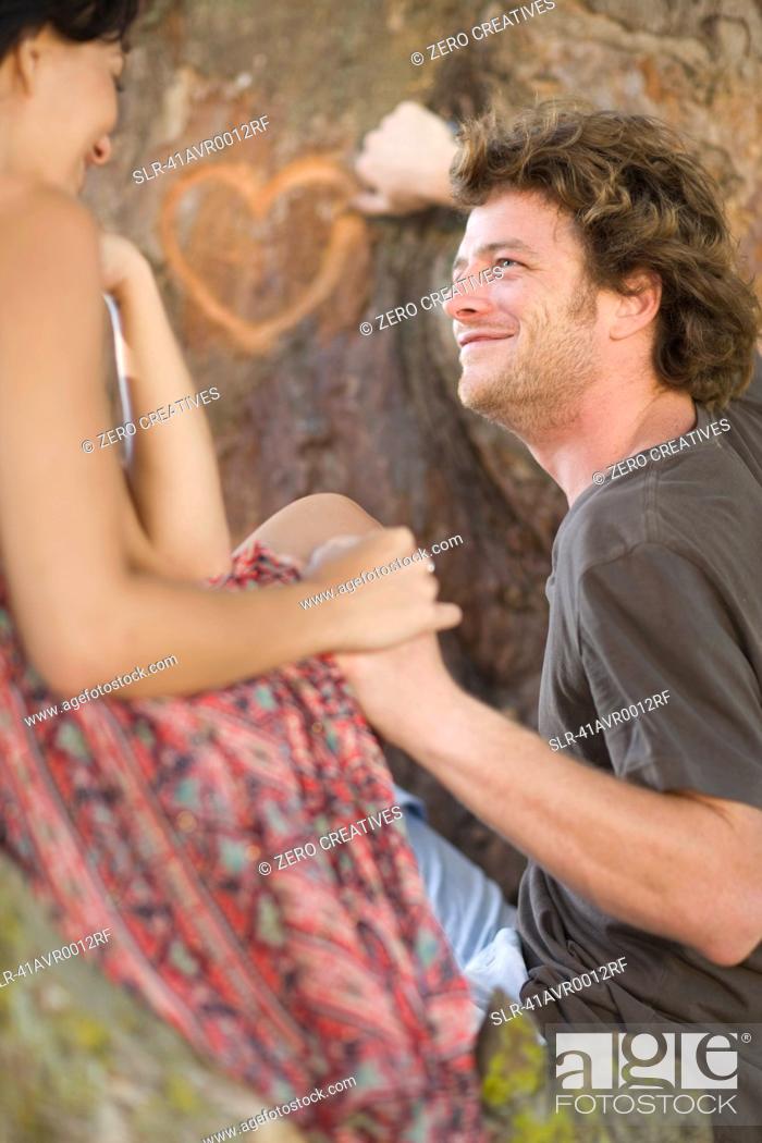 Stock Photo: Couple carving heart in tree.