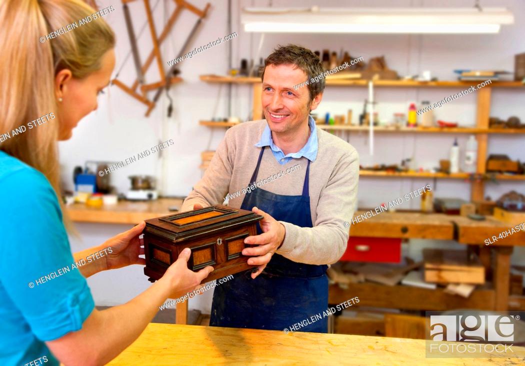 Stock Photo: Carpenter giving jewelry box to client.