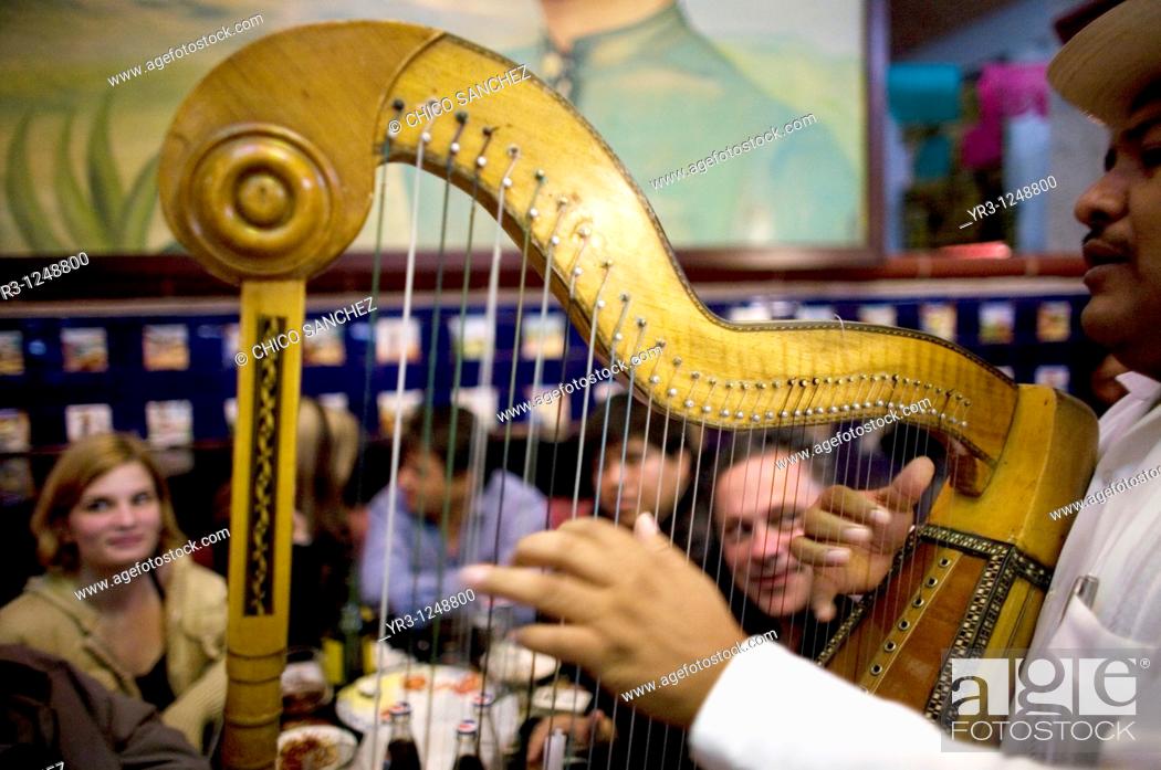 Stock Photo: Tourists watch a harp player perform in the Tenampa restaurant, a famous Mariachi joint in Mexico City.