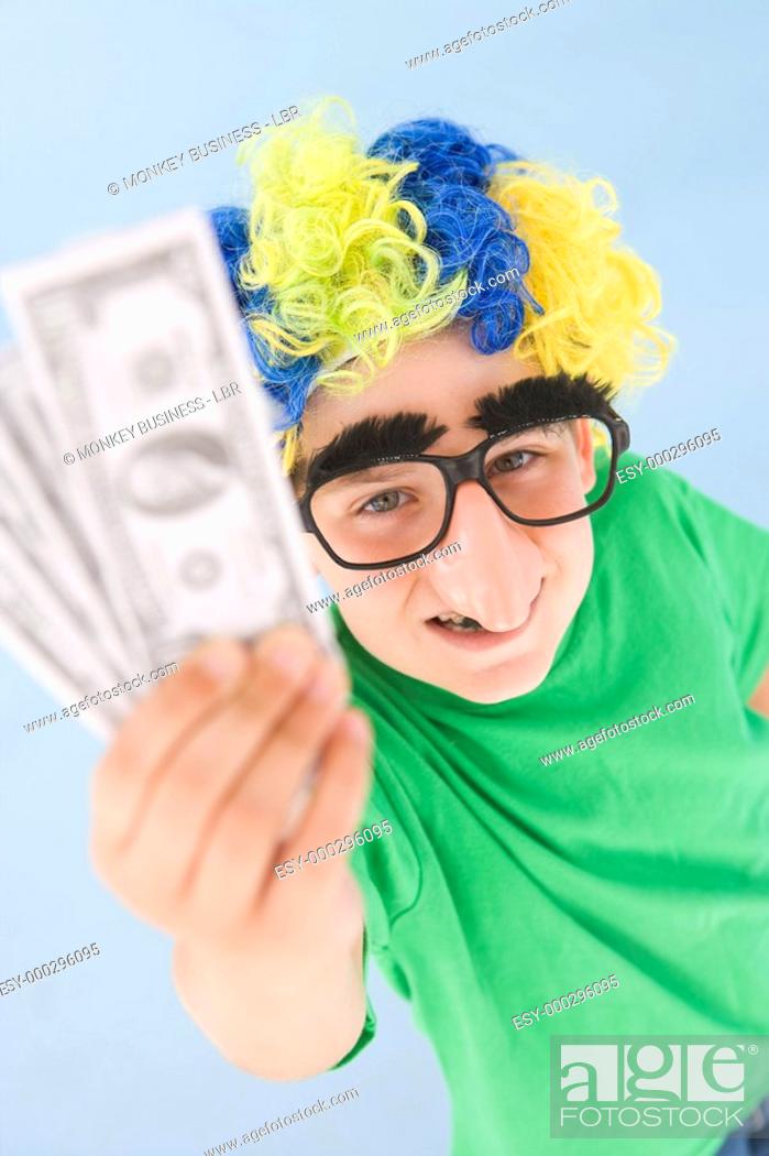 Imagen: Young boy wearing clown wig and fake nose holding money.