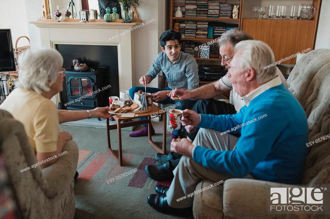 Stock Photo: Teenage boy is assisting senior adults having a tea party at a nursing home.