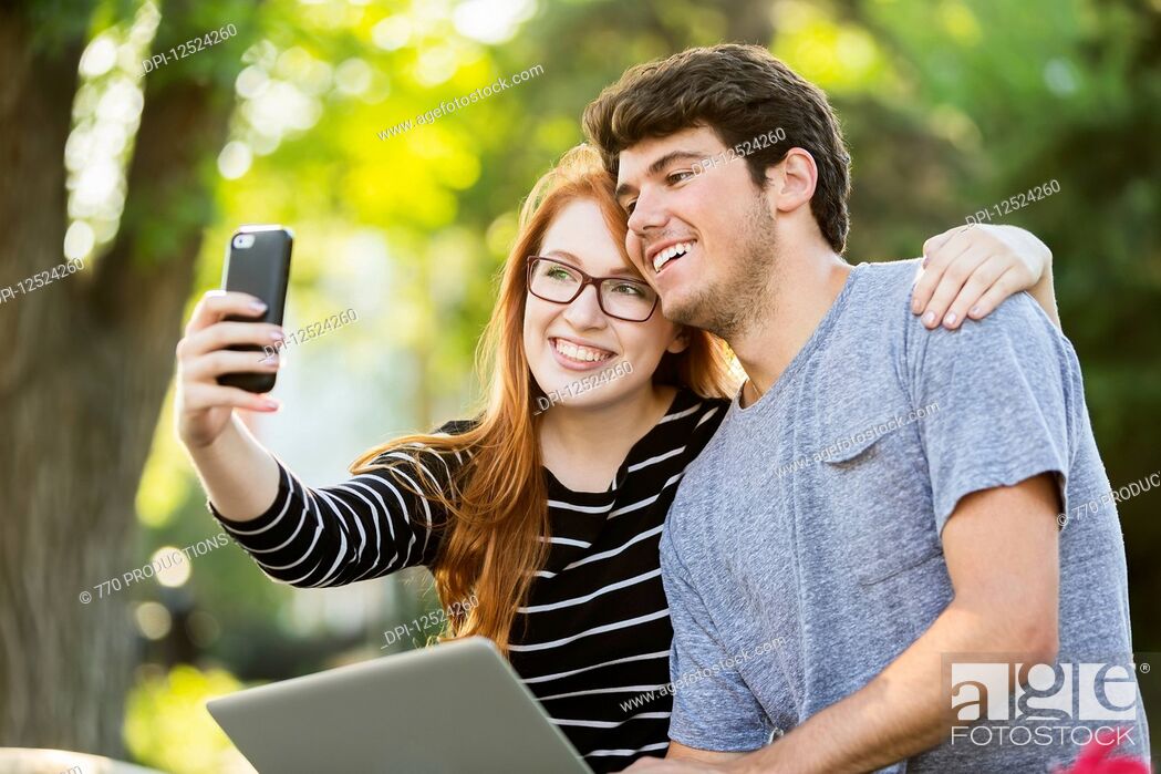 Stock Photo: A young man and young woman taking a self-portrait on a smart phone; Edmonton, Alberta, Canada.