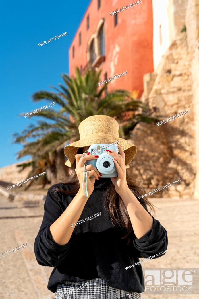 Stock Photo: Portrait of young brunette woman photographing with blue camera.
