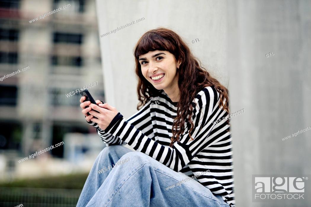 Stock Photo: young woman wearing striped shirt, using smartphone.