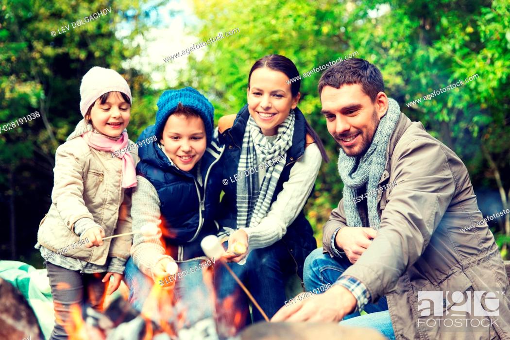 Stock Photo: camping, travel, tourism, hike and people concept - happy family roasting marshmallow over campfire.