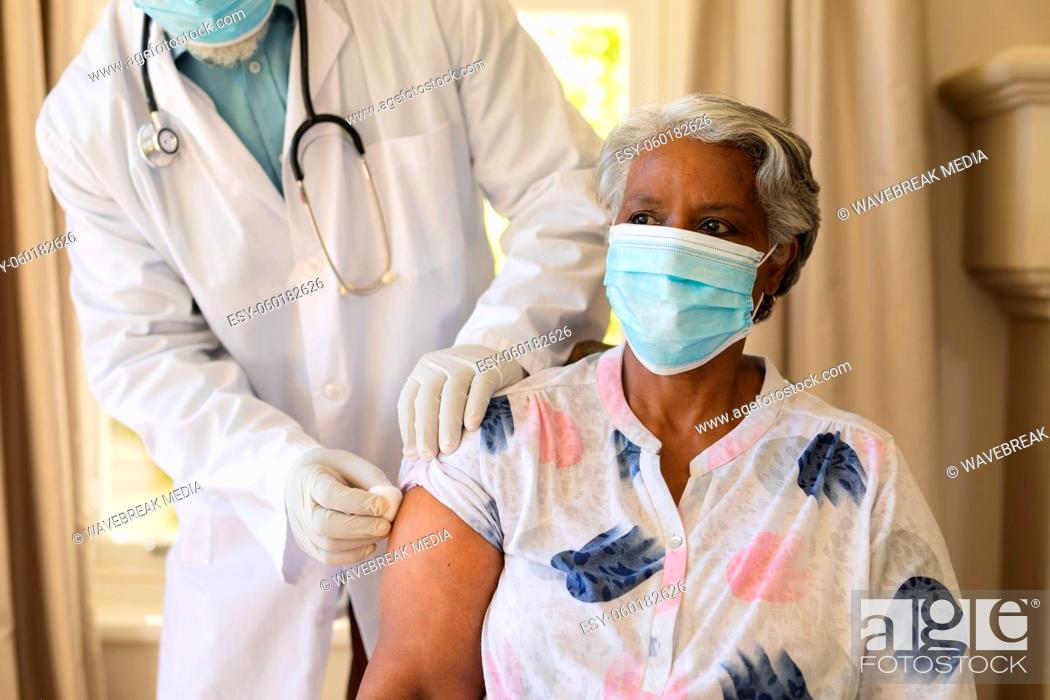 Stock Photo: Senior african american woman in face mask receiving vaccination.