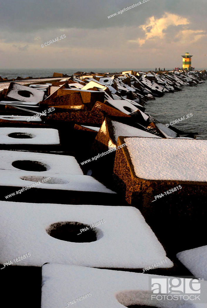 Stock Photo: Late-afternoon sun shining on snow-covered concrete sea defences at Scheveningen harbour's southern promenade pier, the Netherlands.
