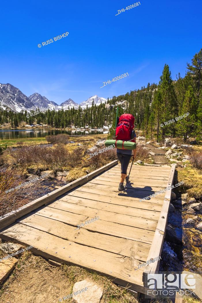 Photo de stock: Woman crossing footbridge over mountain stream in Little Lakes Valley, John Muir Wilderness, California USA.